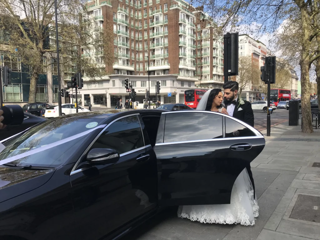 Bride exiting elegant black wedding cab at venue